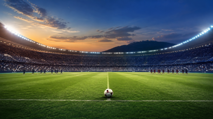 Ilustración editorial de un estadio de fútbol al atardecer, con un balón en el centro del campo y jugadores genéricos calentando a distancia.